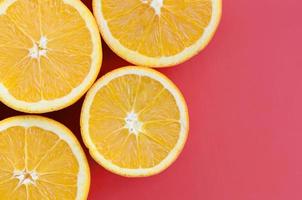Top view of a several orange fruit slices on bright background in red color. A saturated citrus texture image photo