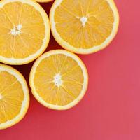 Top view of a several orange fruit slices on bright background in red color. A saturated citrus texture image photo