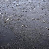 Damaged asphalt road with potholes, filled with water with ice, caused by freezing and thawing in winter. Bad road photo