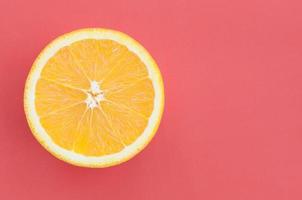Top view of a one orange fruit slice on bright background in red color. A saturated citrus texture image photo