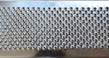 A fragment of a metal chrome grater close-up. Texture of blades for grinding food photo