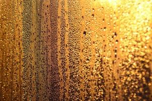 The texture of misted glass with a lot of drops and drips of condensation against the sunlight at dawn. Background image photo