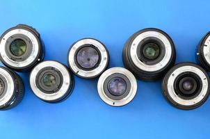 Several photographic lenses lie on a bright blue background. Space for text photo