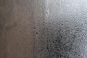 Texture of a drop of rain on a glass wet transparent background. Toned in grey color photo