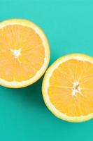 Top view of a several orange fruit slices on bright background in turquoise green color. A saturated citrus texture image photo