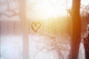 The heart is painted on the misted glass in the winter photo