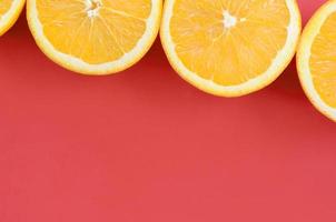 Top view of a several orange fruit slices on bright background in red color. A saturated citrus texture image photo