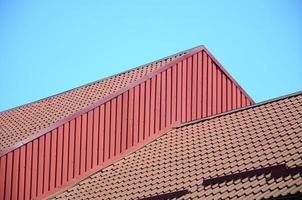 A fragment of a roof from a metal tile of dark red color. Quality Roofing photo