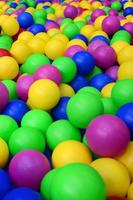 Many colorful plastic balls in a kids' ballpit at a playground. Close up pattern photo