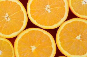Top view of a several orange fruit slices on bright background in orange color. A saturated citrus texture image photo