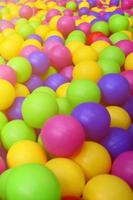 Many colorful plastic balls in a kids' ballpit at a playground. Close up pattern photo