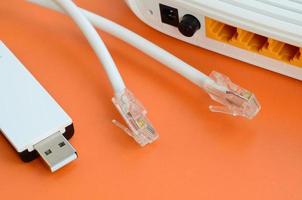 el enrutador de Internet, el adaptador wi-fi usb portátil y los enchufes del cable de Internet se encuentran sobre un fondo naranja brillante. elementos necesarios para la conexión a internet foto