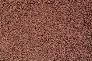 Texture of ground coffee in the form of many small pebbles of dark brown color photo