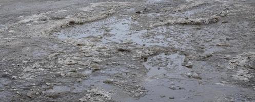 Damaged asphalt road with potholes caused by freezing and thawing cycles during the winter. Poor road photo