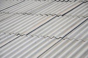 A fragment of a gray slate roof of an old sample made of asbestos material photo