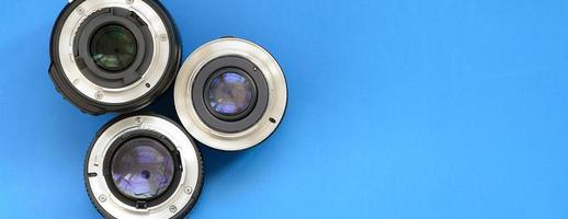 Several photographic lenses lie on a bright blue background. Space for text photo