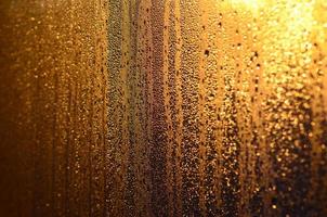 The texture of misted glass with a lot of drops and drips of condensation against the sunlight at dawn. Background image photo