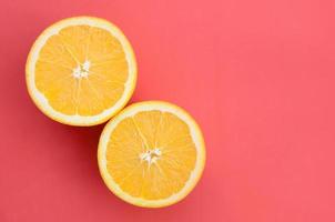 Top view of a several orange fruit slices on bright background in red color. A saturated citrus texture image photo