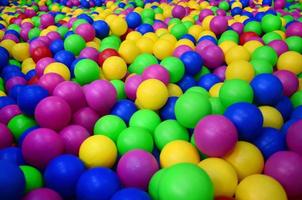 muchas bolas de plástico de colores en una piscina para niños en un parque infantil. patrón de primer plano foto