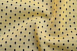 textura de tela de ropa deportiva amarilla y fondo con muchos pliegues foto