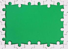 Framing in the form of a rectangle, made of a white jigsaw puzzle around the green space photo