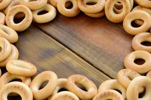 A lot of fresh yellow bagels lie on the surface of the old dark wood. A popular kind of flour products. One of the traditional Russian treats for tea photo