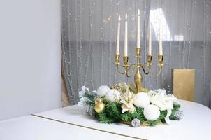New Year's decorations and a golden candlestick with burning candles stand on the surface of a white grand piano photo