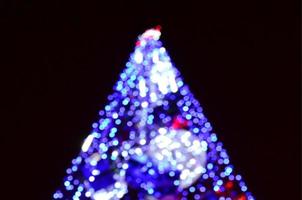 Blurred fragment of the New Year tree. Lots of round lights in blue photo