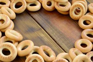 A lot of fresh yellow bagels lie on the surface of the old dark wood. A popular kind of flour products. One of the traditional Russian treats for tea photo