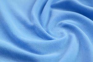 The blanket of furry blue fleece fabric. A background of light blue soft plush fleece material with a lot of relief folds photo