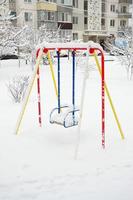 Children's swing, covered with a thick layer of snow after a heavy snowfall photo