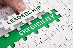 The human hand fills the last missing elements of the surface from the jigsaw puzzle. Image with words leadership and credibility photo