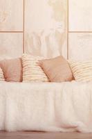 muchas almohadas yacen en el sofá, que está cubierto con un gran velo de felpa contra el fondo de una pared de mármol foto