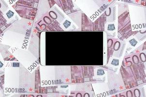 Purple 500 euro money bills and a smartphone with black screen. Copy space. The concept of online banking, money management and shopping with modern technology photo