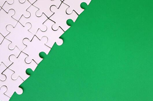 fragmento de un rompecabezas blanco doblado sobre el fondo de una superficie de plástico verde. foto de textura con espacio de copia para texto