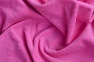 The blanket of furry pink fleece fabric. A background of light pink soft plush fleece material with a lot of relief folds photo
