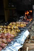 la carne cruda y las patatas se plantan en brochetas de metal. el proceso de cocinar shish kebabs. comida de campamento rusa y ucraniana foto