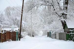un paisaje rústico de invierno con algunas casas antiguas y una amplia carretera cubierta con una gruesa capa de nieve foto