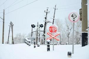 deténgase. la señal de carretera roja se encuentra en la autopista que cruza la línea ferroviaria en la temporada de invierno foto