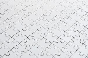 Close up of a white jigsaw puzzle in assembled state in perspective. Many components of a large whole mosaic are united photo