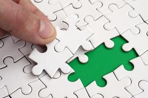 The human hand fills the last missing elements of the surface from the jigsaw puzzle. The concept of the completion of the initiated cases photo