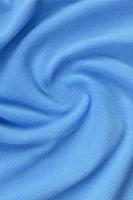 The blanket of furry blue fleece fabric. A background of light blue soft plush fleece material with a lot of relief folds photo