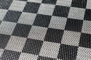 Plastic texture in the form of a very small cloth binding, painted in black and gray in the style of a chessboard. Macro shot photo