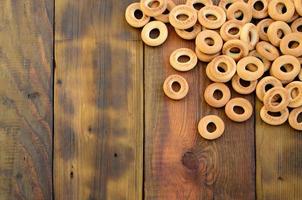 A lot of fresh yellow bagels lie on the surface of the old dark wood. A popular kind of flour products. One of the traditional Russian treats for tea photo