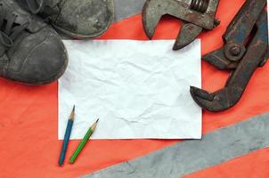 Adjustable wrenches with old boots and a sheet of paper with two pencils photo