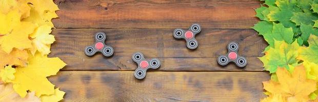 Several spinners among the many yellowing fallen autumn leaves on the background surface of natural wooden boards of dark brown color photo