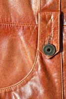 Brown leather texture. Useful as background for any design work. Macro photo of a button on outer clothing made of genuine leather