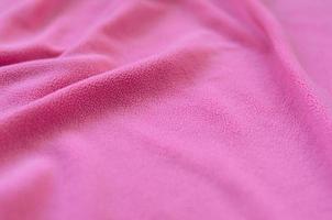 The blanket of furry pink fleece fabric. A background of light pink soft plush fleece material with a lot of relief folds photo