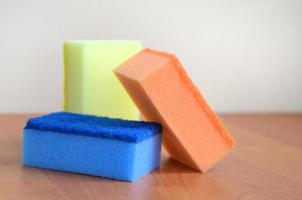 A few kitchen sponges lie on a wooden kitchen countertop. Colorful objects for washing dishes and cleaning in the house are ready for use photo