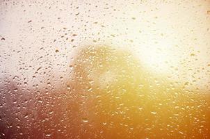 Background image of rain drops on a glass window. Macro photo with shallow depth of field. Toned picture